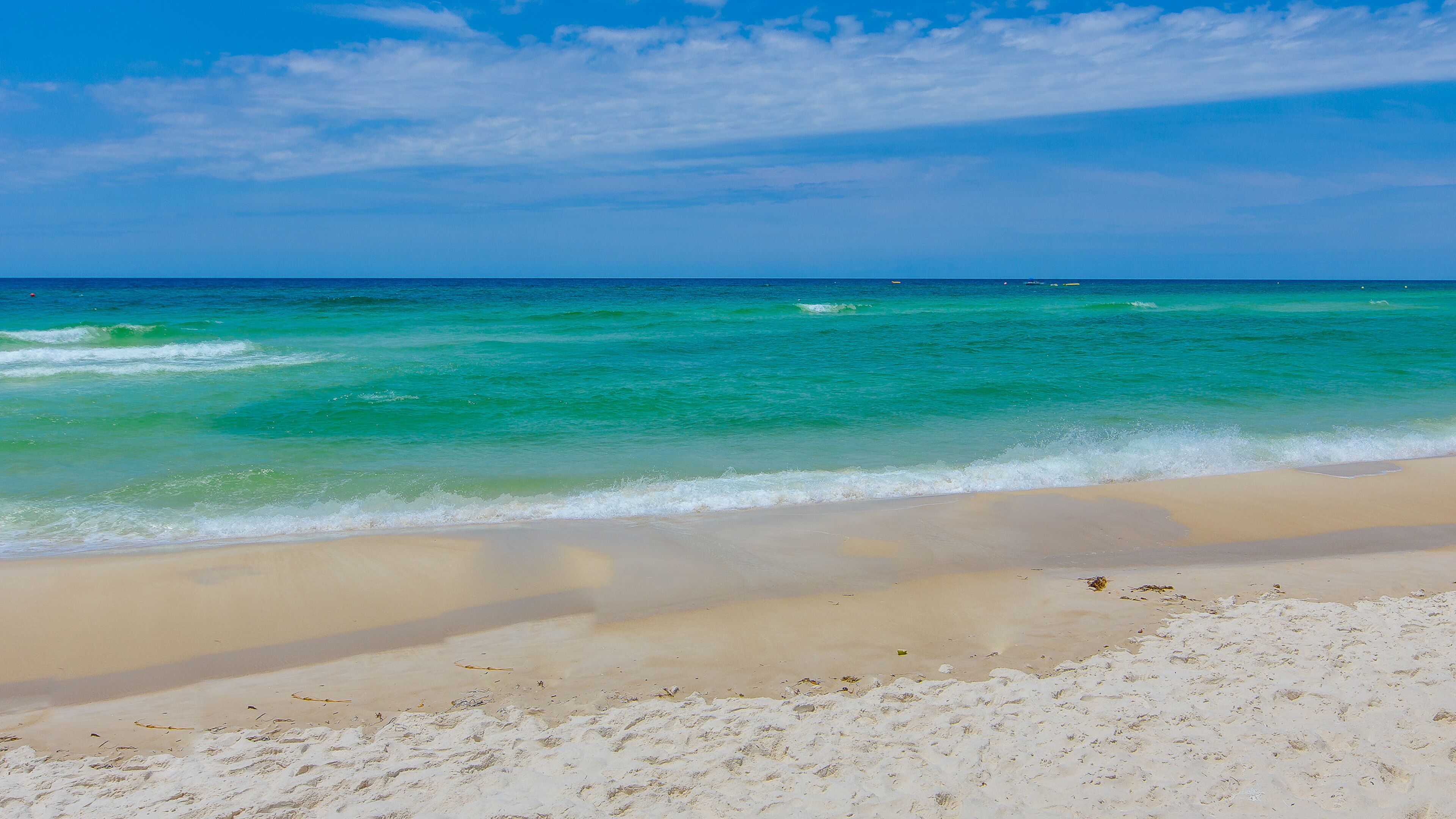 Une plage à l’eau turquoise et limpide, bordée d’un rivage sablonneux.