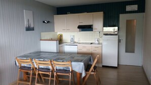 A compact kitchen with a dining table and chairs, a sink, a coffee maker, and a refrigerator.