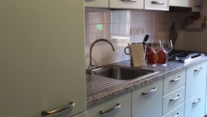 Une cuisine avec des armoires blanches, un comptoir en granit, un évier en acier inoxydable et une cuisinière.