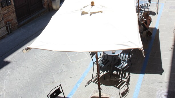 Une rue bordée de terrasses, avec des bâtiments en briques et un ciel dégagé.