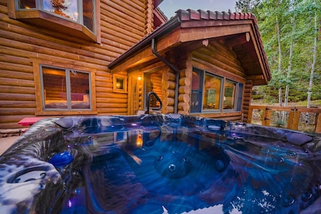 A log cabin with a hot tub in front.