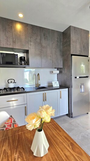 A modern kitchen with a stainless steel refrigerator, a gas stove, and a coffee maker.