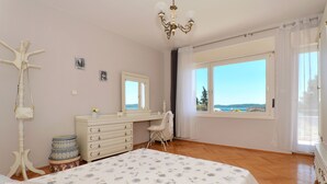 Un dormitorio con una cama grande, un aparador, una silla y un ventanal con vistas.