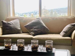 Relax in a serene living area with a sofa, side table, and scenic views of the hilly landscape.