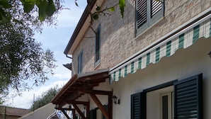 A building with a stone facade, a wooden staircase, and a covered outdoor area. - Total tranquility in the hills of Budoni (San Lorenzo)
