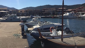 A marina with boats docked, a clear sky, and buildings in the background. - Total tranquility in the hills of Budoni (San Lorenzo)