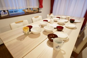 Enjoy meals in this elegant dining area with a long table, white plates, and comfortable chairs.