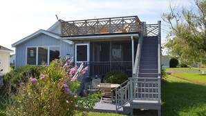 A house with a covered porch, outdoor seating, and a staircase leading to a deck.