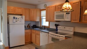 A kitchen with wooden cabinets, a refrigerator, a microwave, a dishwasher, and a stove.