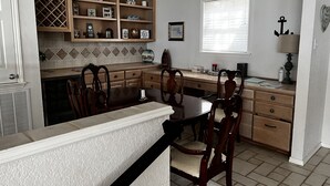 Une cuisine équipée d’une table à manger, de chaises, d’une étagère intégrée et d’une fenêtre avec des stores.