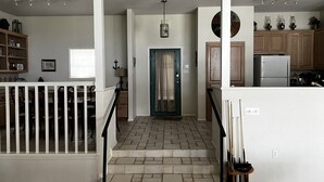 Un intérieur de maison comprenant une cuisine, un coin repas et un escalier menant à un deuxième étage.