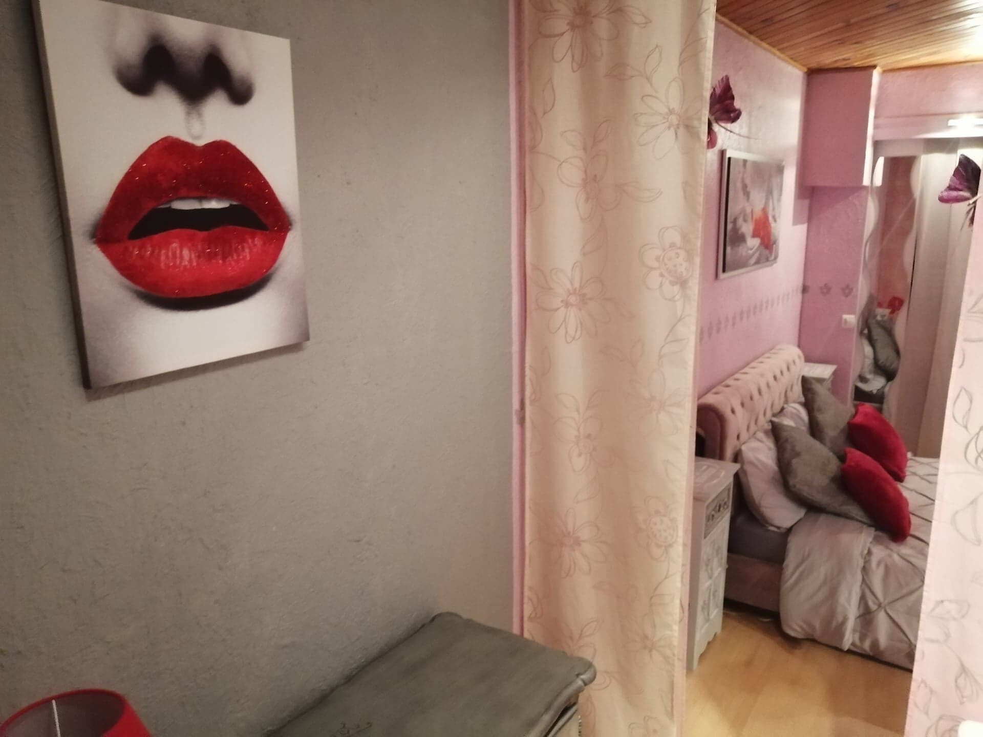 Una habitación con una cama, un sofá, una mesita y un cuadro de labios en la pared.