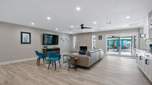 Un amplio espacio de sala con sofá, sillas, televisión y chimenea.