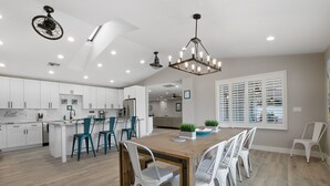 Una cocina moderna con armarios blancos, una mesa de comedor de madera y sillas color turquesa.
