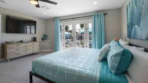 Un dormitorio con cama, ventilador de techo, cómoda y vista al exterior.
