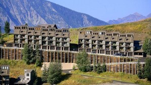 Un edificio moderno de varios pisos con un diseño modular único, con montañas al fondo.