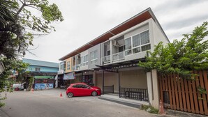 A two-story building with a covered entrance and a red car parked in front. - OYO 75323 Tha Burapa Home Bangsean (Chonburi)
