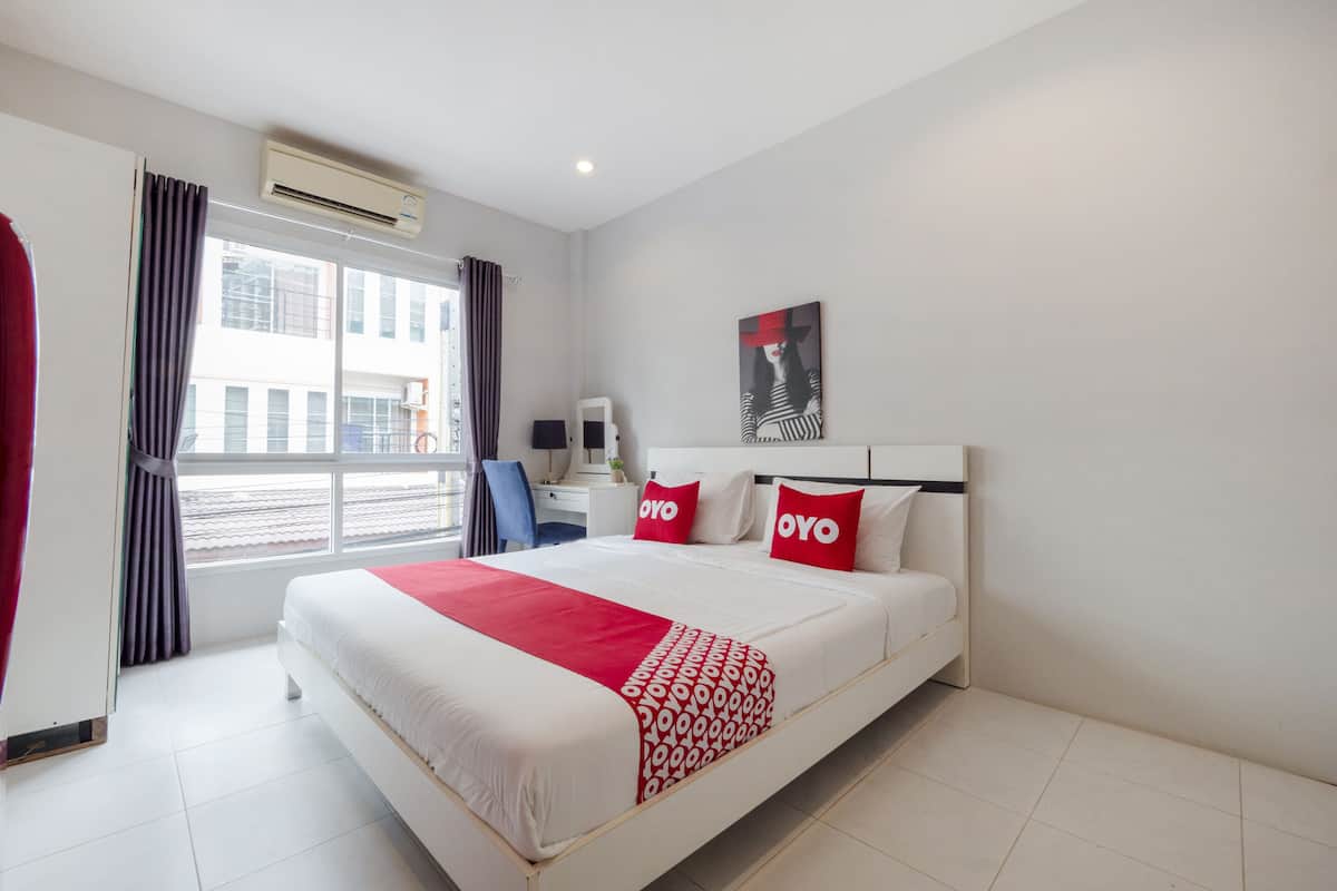 A hotel room with a bed, a desk, a chair, and a window with curtains.