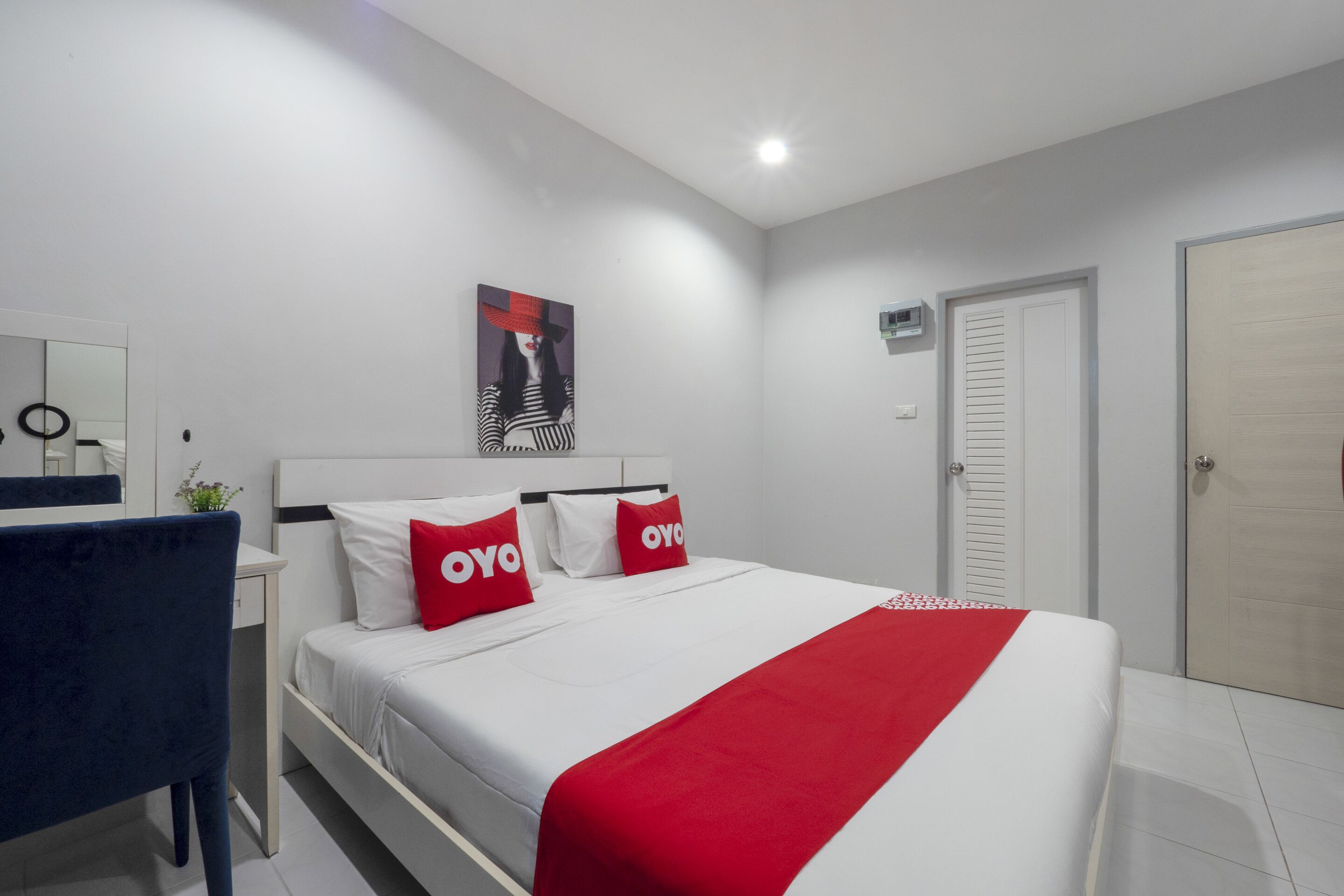 A modern hotel room with a neatly made bed, a desk, and a chair.