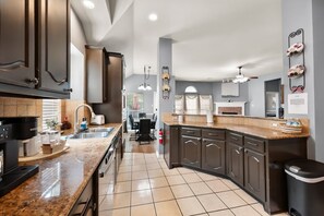 Cocina moderna con encimeras de granito, armarios oscuros y una isla central.