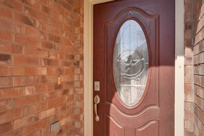 Una porta rossa con un vetro e una maniglia in ottone.