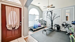 Une salle de sport à domicile équipée d’un tapis de course, de ballons d’exercice et de matériel de musculation.