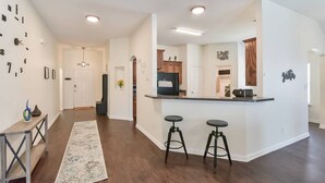 A modern kitchen with a central island, bar stools, and a decorative clock on the wall.