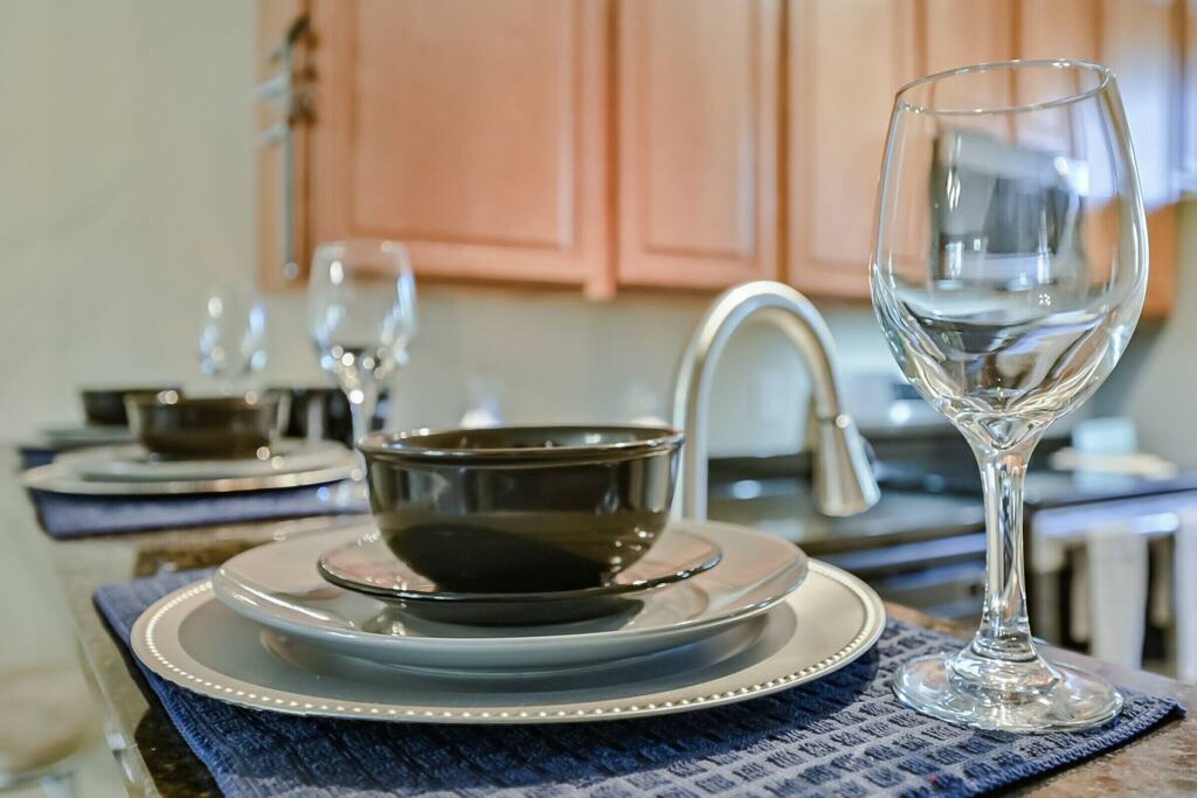 A kitchen with a sink, a stove, and a dining area with a table set for two.