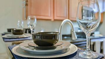 A kitchen with a sink, a stove, and a dining area with a table set for two.