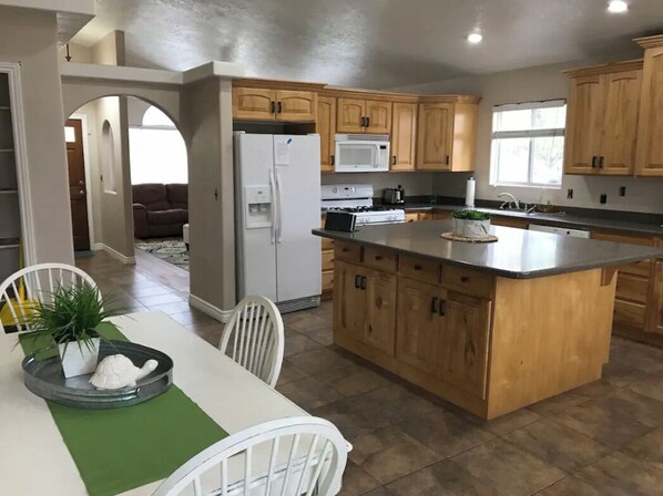 Enjoy meals in this kitchen with a central island, dining area, and large window offering a view of the outdoors.