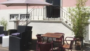 A pink building with a wooden deck, outdoor seating, and a staircase leading to the entrance. - Hotel Rural Quinta do Juncal (Peniche)