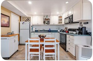 A compact kitchen with white cabinets, a central island, a microwave, and a coffee maker.