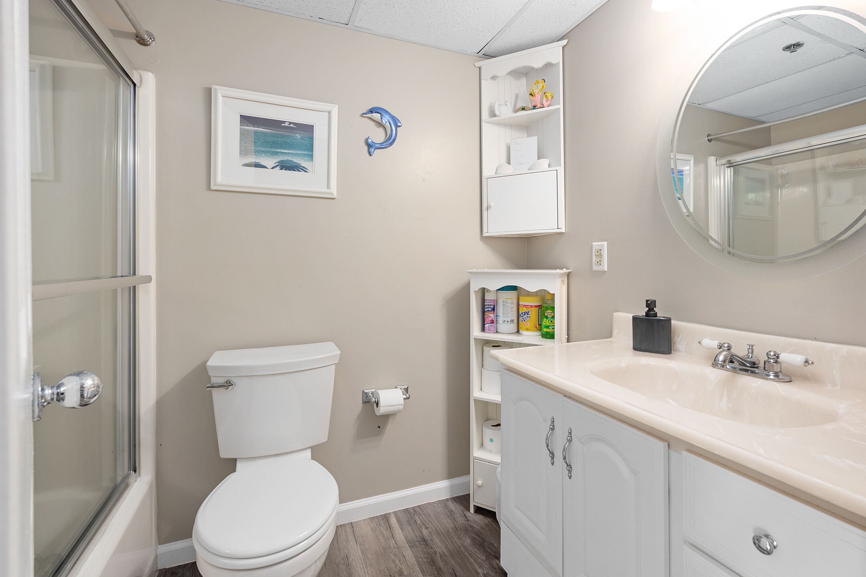 A bathroom with a toilet, a shower, a sink, and a mirror.