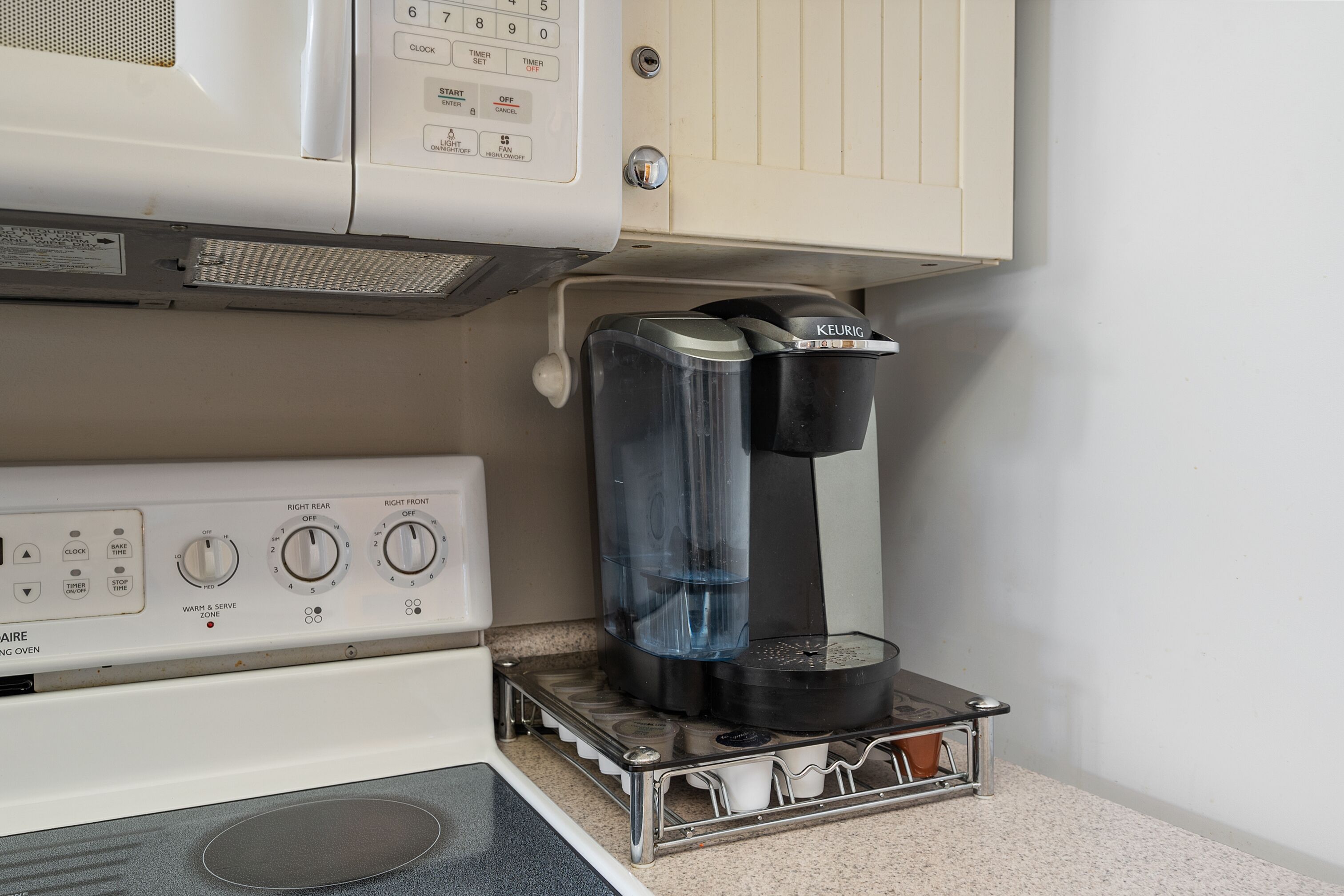 A kitchenette with a coffee maker, a microwave, and a stove.