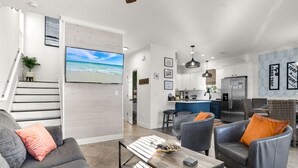 A modern living room with a grey sofa, a coffee table, and a TV displaying a beach scene. - Best Lagoon Pool View in Destin • Walk to the Beach • Spacious Stay (Destin)