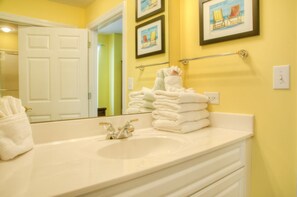 A bathroom with a large white sink, a mirror, and a towel rack with neatly folded towels.
