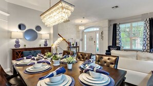 A dining room with a wooden table set for six, surrounded by leather chairs. A chandelier hangs from the ceiling, and there are decorative mirrors on the wall. - Large Windsor Hills Resort pool/Spa Home- Disney (Kissimmee)
