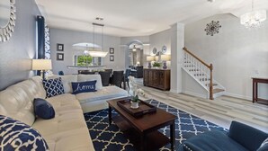 A living room with a sofa, coffee table, and a staircase leading to another level. - Large Windsor Hills Resort pool/Spa Home- Disney (Kissimmee)