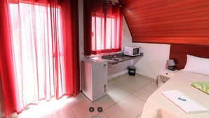 A compact hotel room with a kitchenette, a bed, and a small bedside table. - Espaço Chalé Cereja (Cachoeira Paulista)