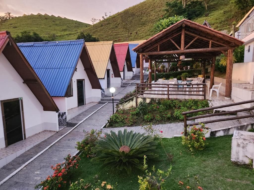 Um pátio com área de estar coberta, um caminho e um pequeno jardim com uma planta grande e flores.