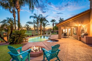 Un jardin avec une piscine, un foyer extérieur, un espace salon extérieur et un coin barbecue.