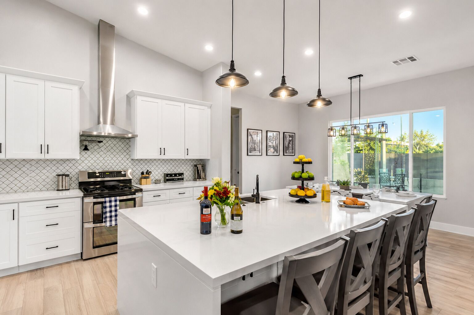 A modern kitchen with white cabinetry, stainless steel appliances, and a central island with seating.