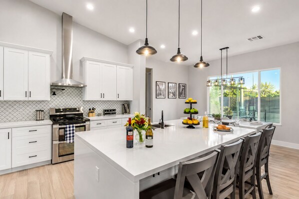 A modern kitchen with white cabinetry, stainless steel appliances, and a central island with seating.