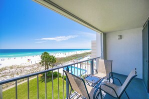 Un balcon avec vue sur une plage et une piscine.