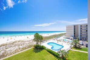 A hotel with a pool, beach view, and a parking area.