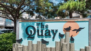 Une enseigne portant l’inscription « The Quay » et des silhouettes d’oiseaux.