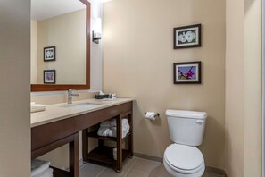 A bathroom with a sink, mirror, toilet, and two framed pictures on the wall.