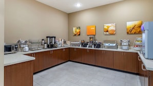 A modern kitchen with wooden cabinets, a microwave, coffee maker, and various appliances.