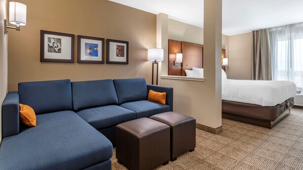 A hotel room with a large sofa, a bed, and a small table.