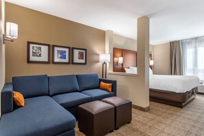 Ein Hotelzimmer mit einer großen Couch, einem Bett und einem kleinen Tisch.